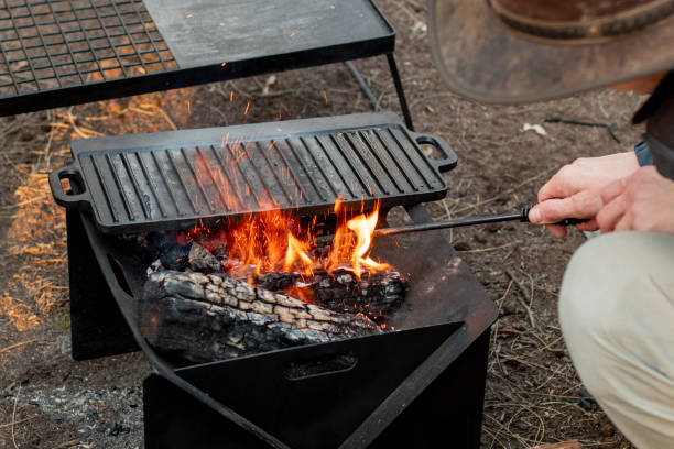 Setting the campfire in a portable foladble firepit for a camp cooking on cast iron plate